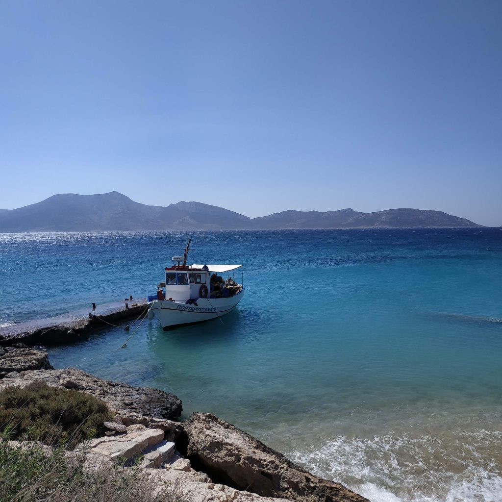 Petit bateau de pêche amarré dans une crique turquoise à Koufounissa, idéal pour un voyage en Grèce en famille au calme